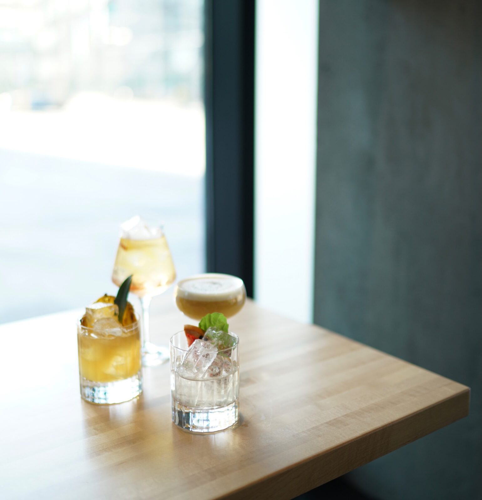 Three cocktails arranged on a wood table