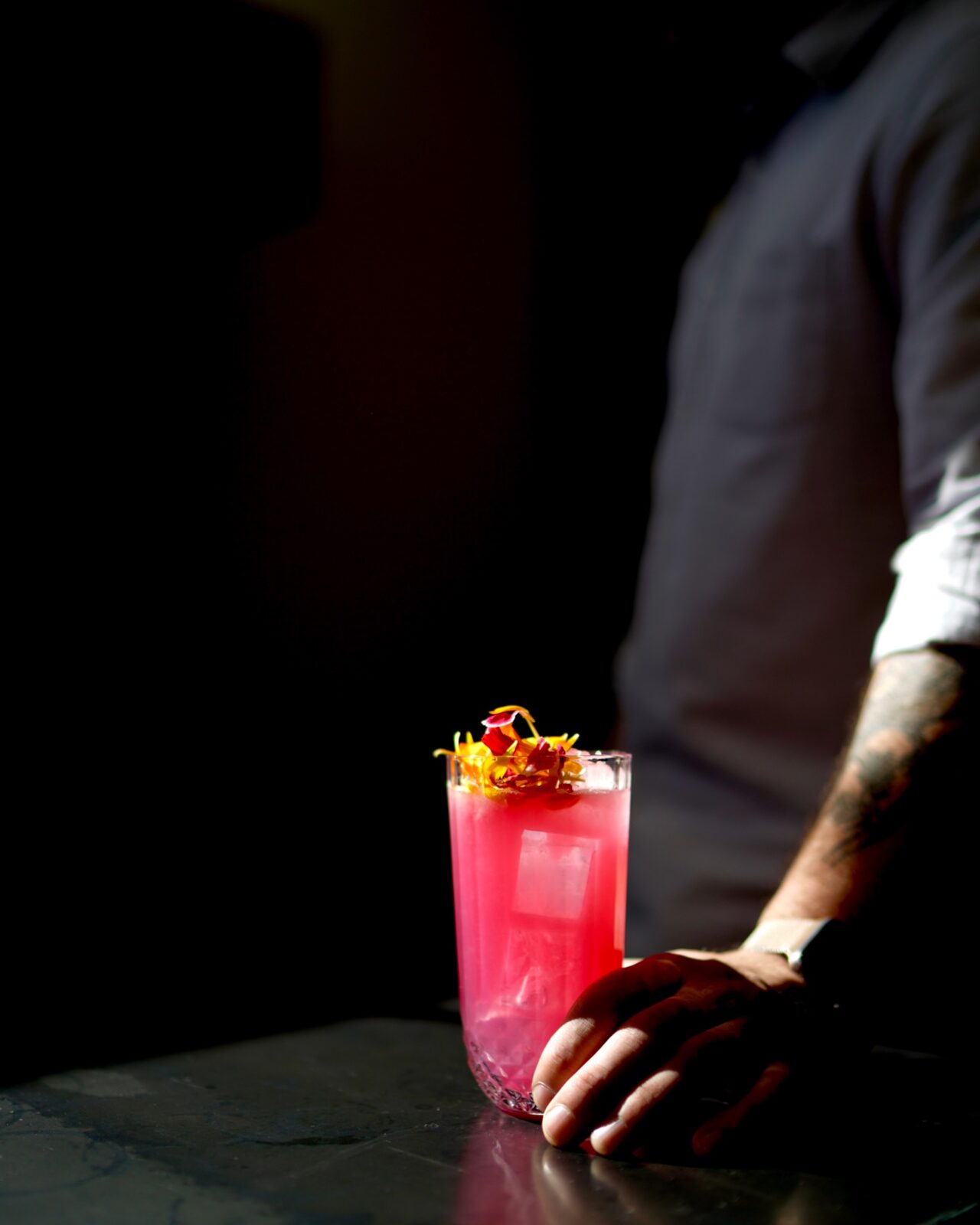 A vivid red cocktail illuminated against a dark background