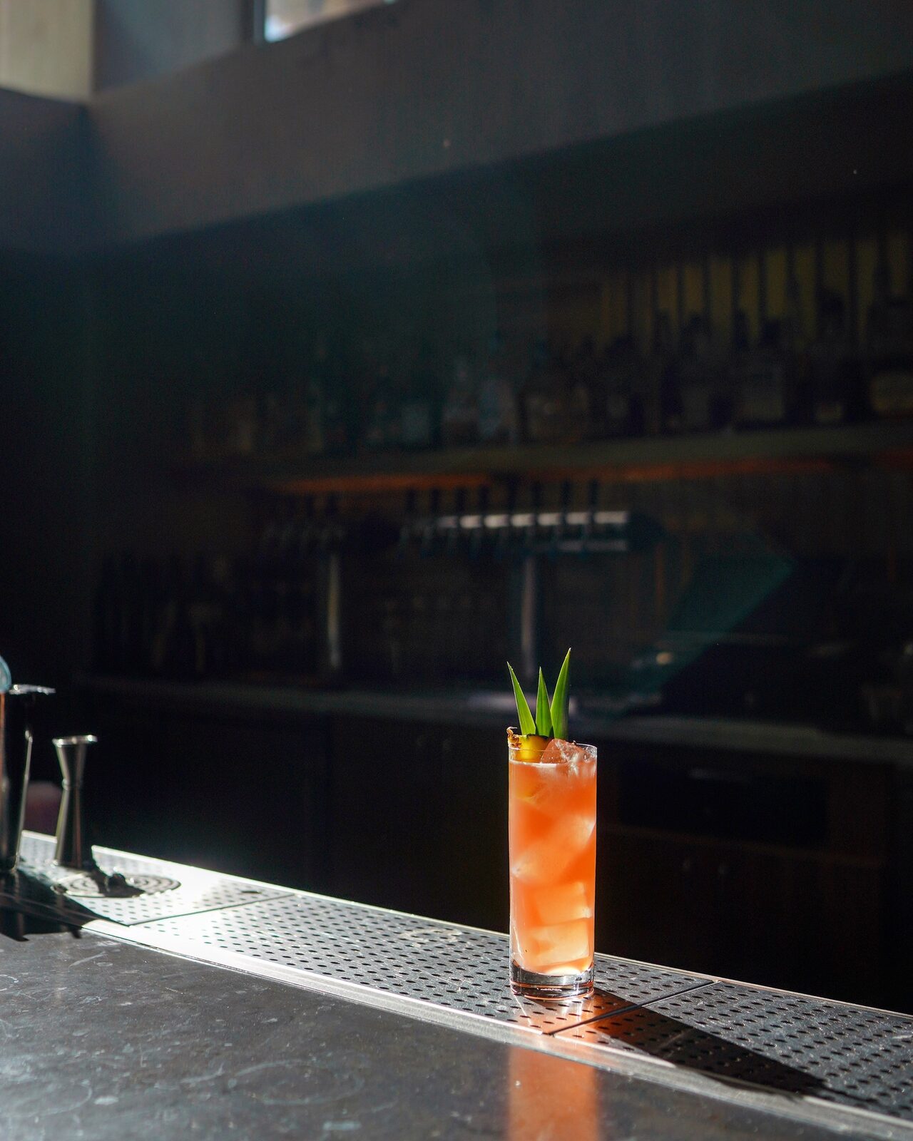 A tall cocktail resting on a dimly lit bar